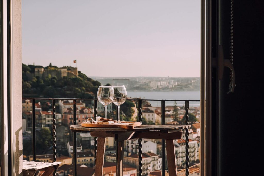 balkon met uitzicht op een oude stad in de heuvels en twee glazen rozé wijn.